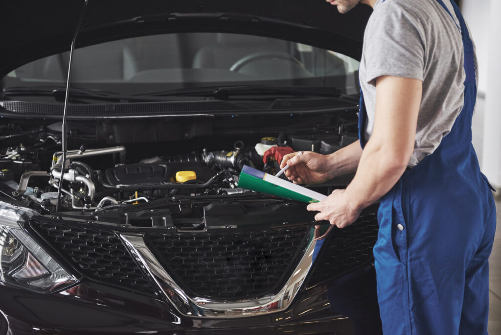 Portrait of a mechanic at work in his garage - car service, repair, maintenance and people concept