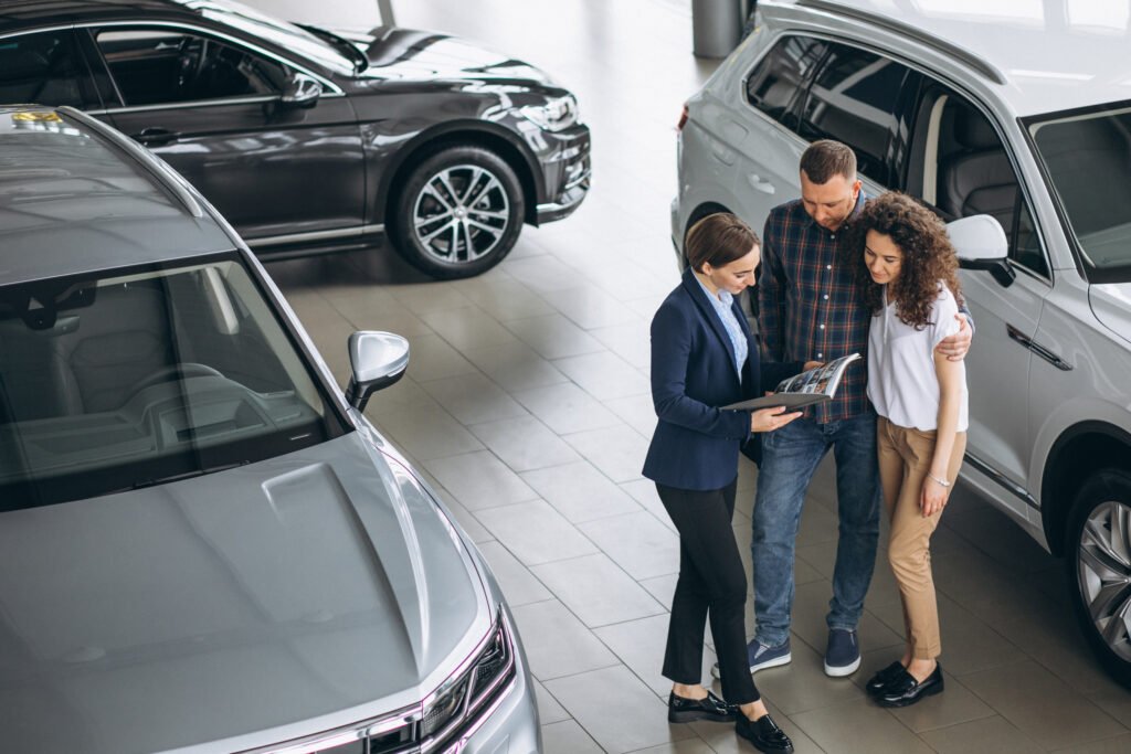 Young couple talking to a sales person in a car showroom Otomobil